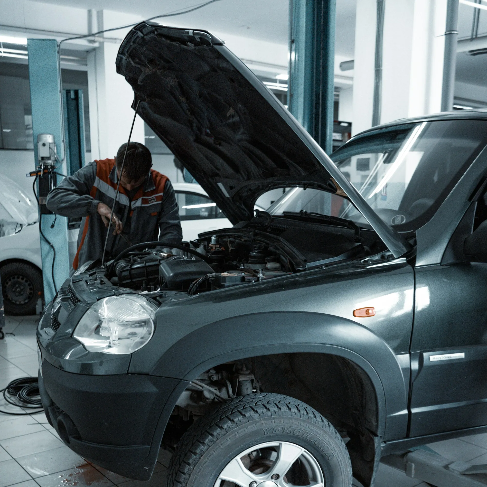 Technician leaning into the engine bay of a grey SUV